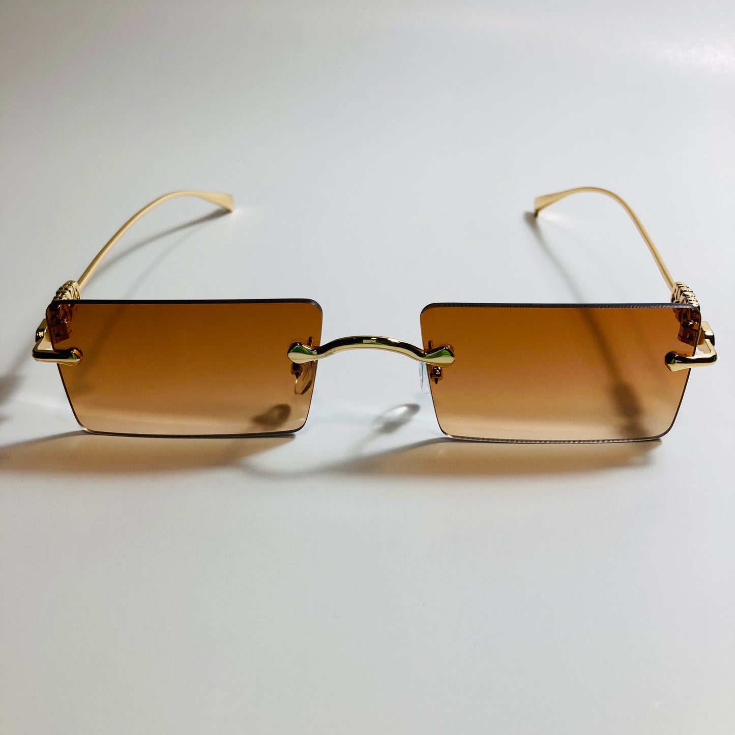 gold rimless womens sunglasses with brown lenses and flower accent